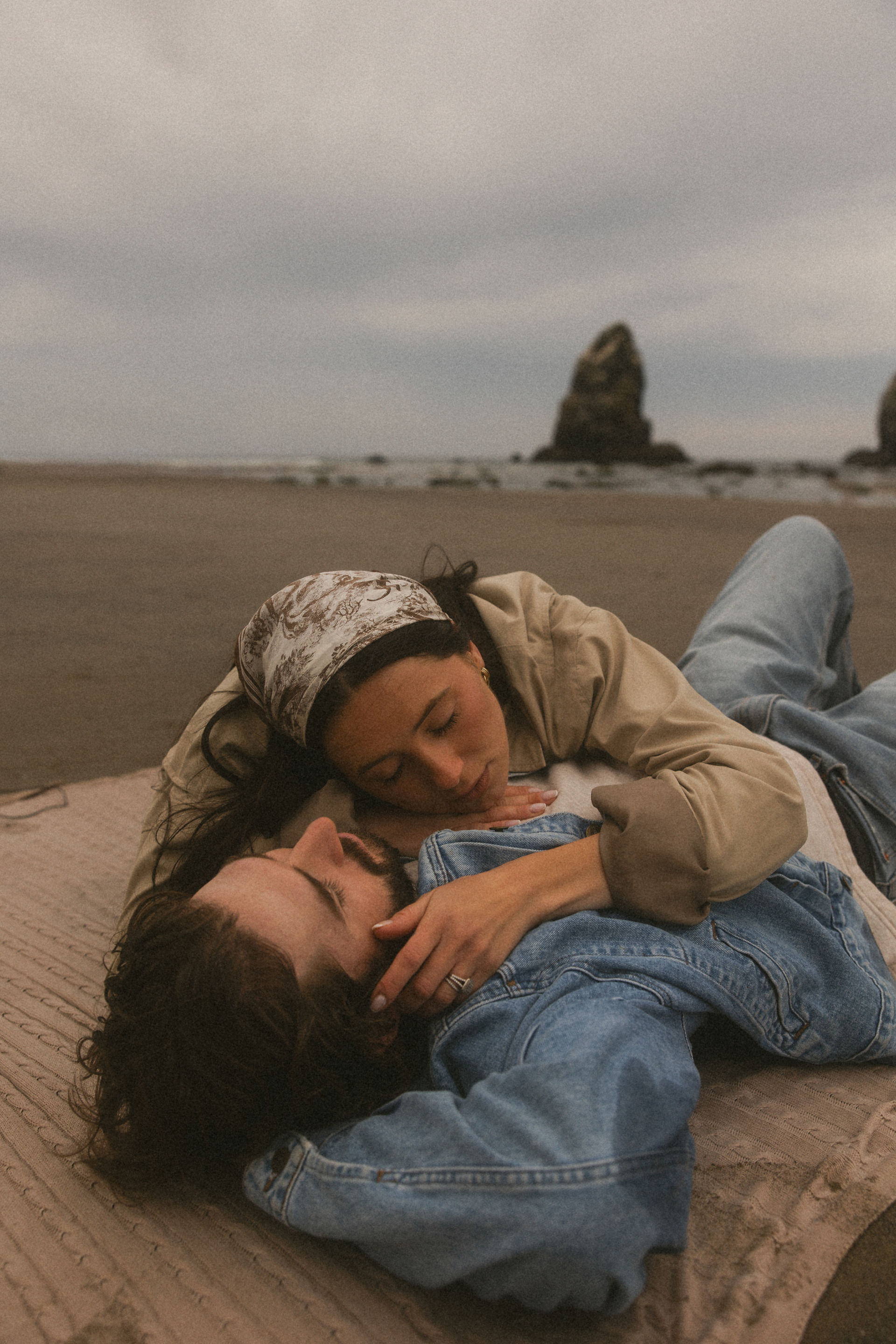 A girl laying on her husband's chest for a beach photoshoot