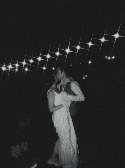 Bride and groom dancing under string lights at their backyard wedding