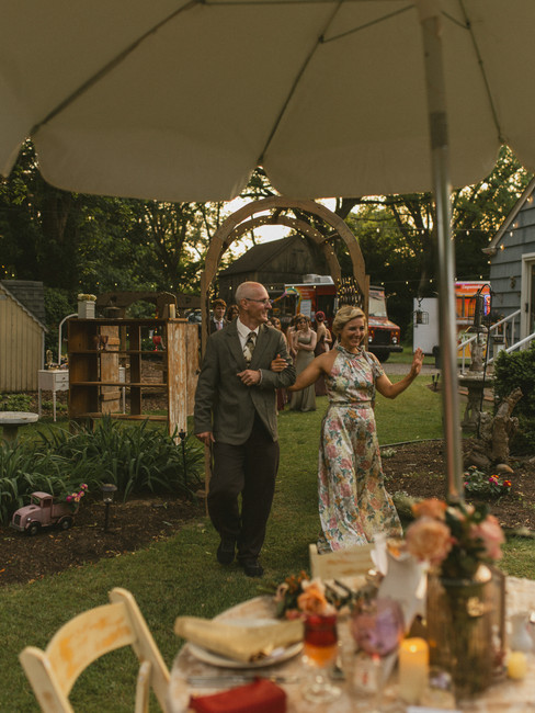 A documentary style wedding photography photo of guests entering a backyard wedding reception