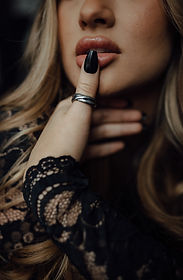 A close-up of a woman’s lips with black polished nails and silver rings, evoking bold editorial artistry tied to destination wedding photography prices.
