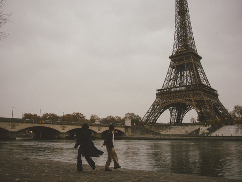 A couple running during a Paris photoshoot in front of the Eiffel Tower