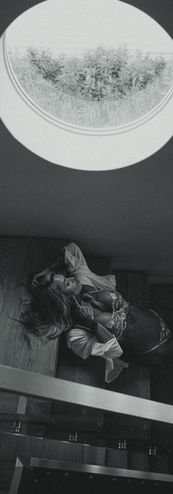 
Black and white boudoir portrait of a woman reclining in lace lingerie by a window and ornate mirror, photographed with the same artistic eye as cinematic wedding photography.
