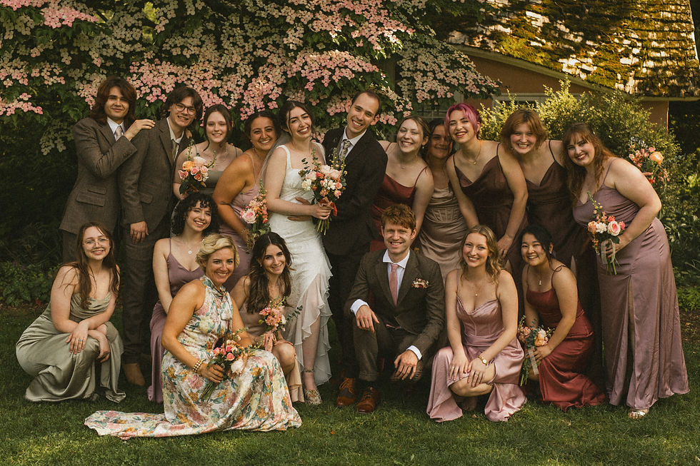A bridal party photo with wedding party squatting around the couple in varying shades of pink and green