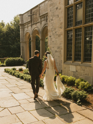 A bride and groom walking through stone path at West Portico at Planting Fields Arboretum