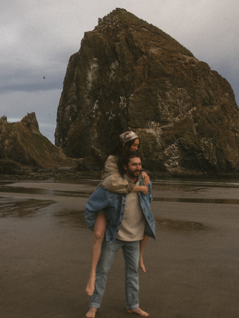 A woman on her husband's back at Cannon Beach photoshoot
