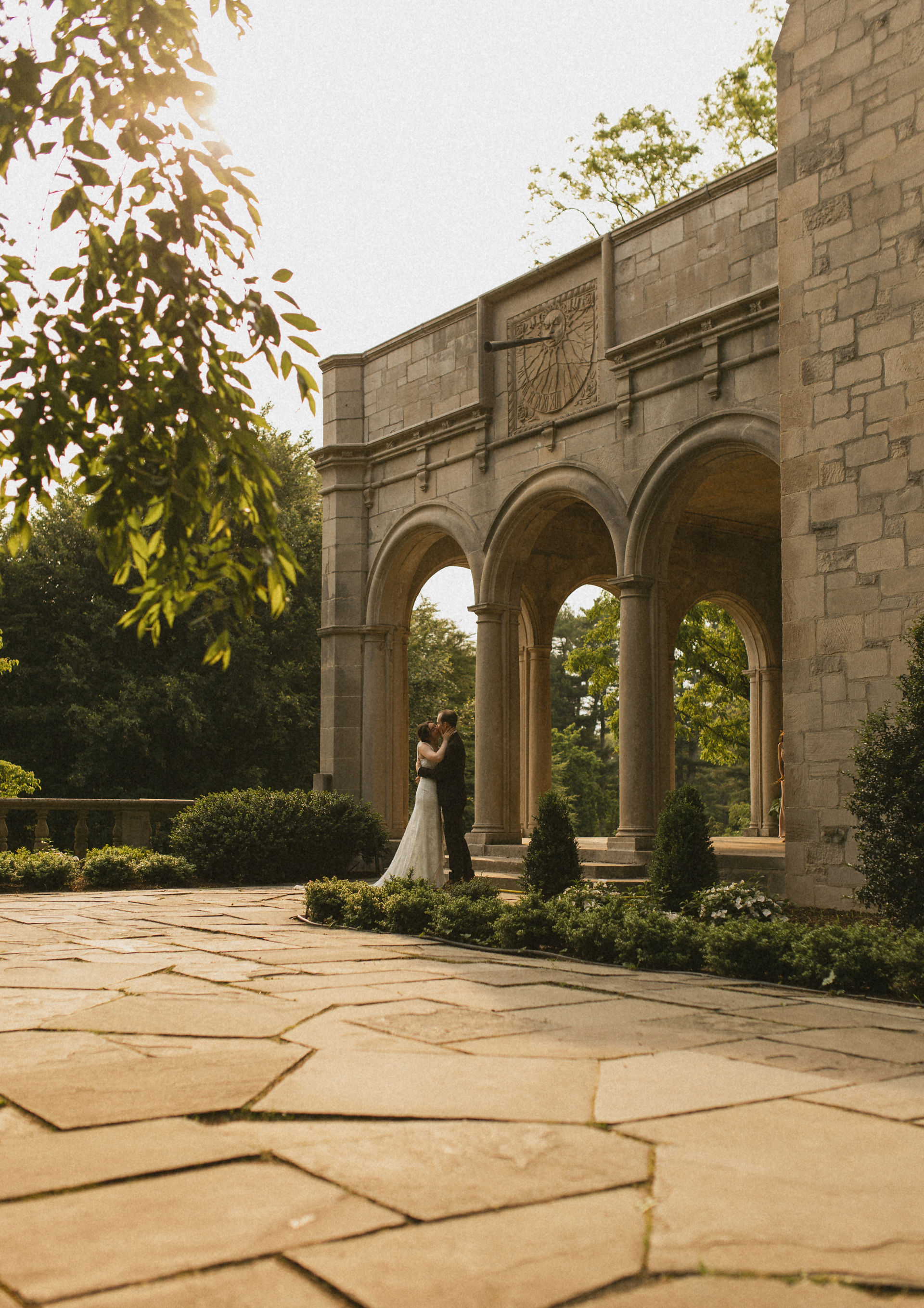 A bride and groom under stone arches at Planting Fields Arboretum