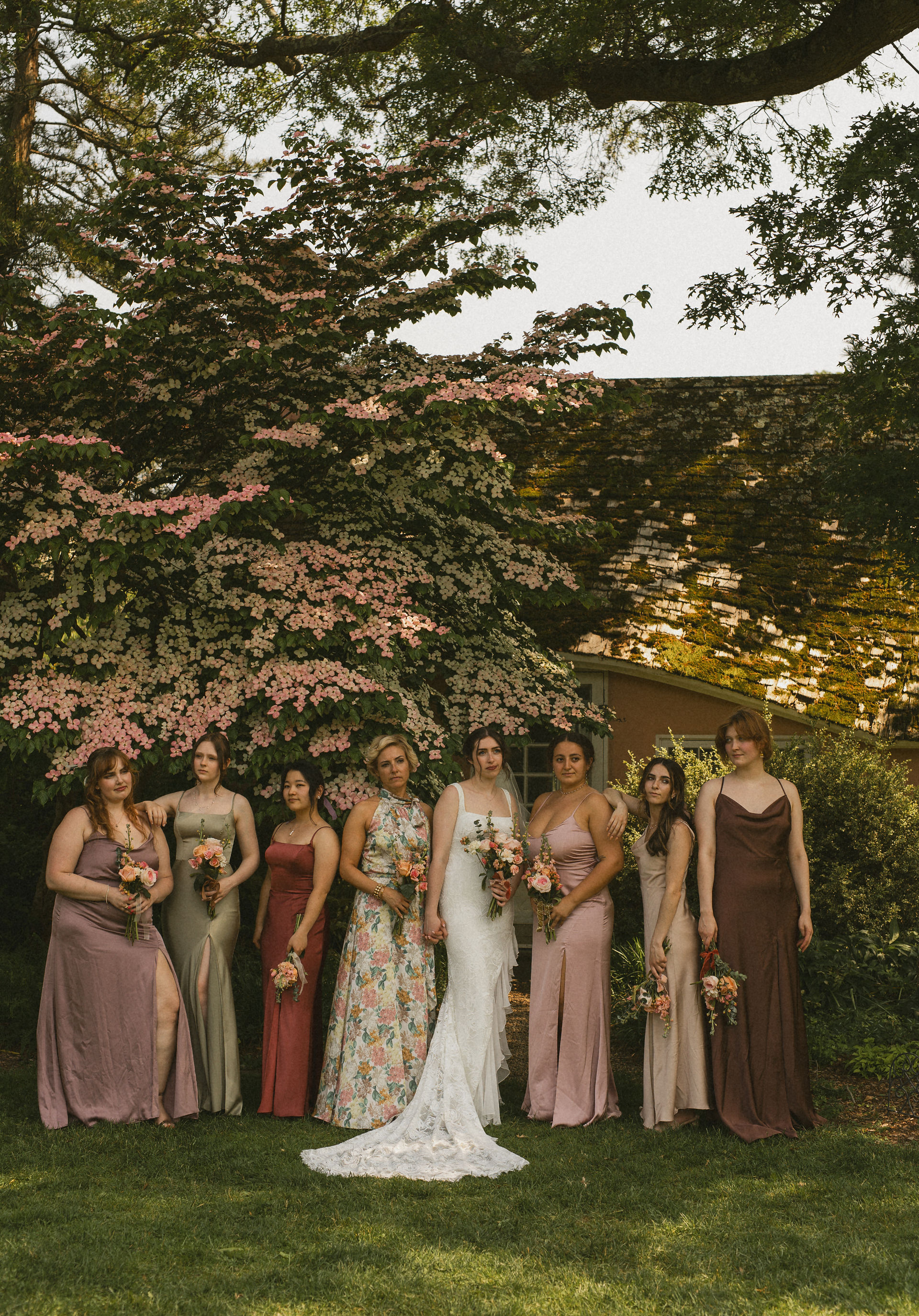 A wedding party photo at planting fields arboretum with bridesmaids in pink, green, and brown bridesmaid dresses