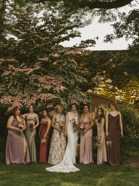 A wedding party photo at planting fields arboretum with bridesmaids in pink, green, and brown bridesmaid dresses