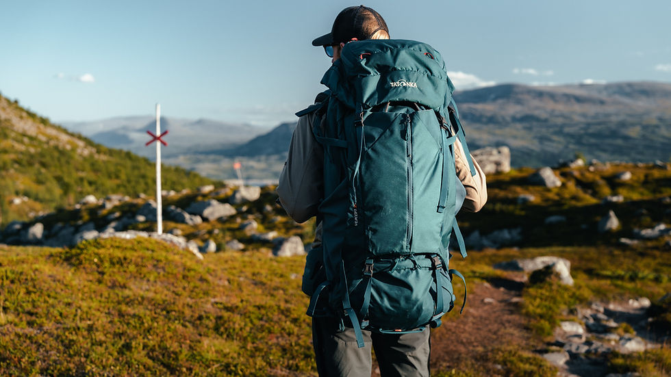 A hiker is wearing a big backpack in a rocky terrain.