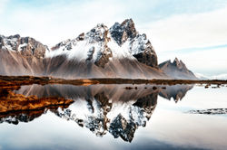 Das Vestrahorn in Island spiegelt sich in einer Pfütze.