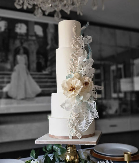 A 4 tier cream and mint wedding cake design with wafer flowers and lace