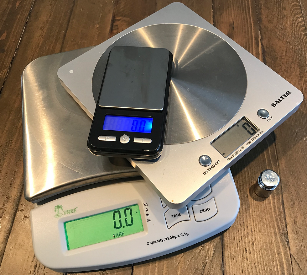 Image shows three electronic kitchen scales stacked on top of each other on top of a wooden table