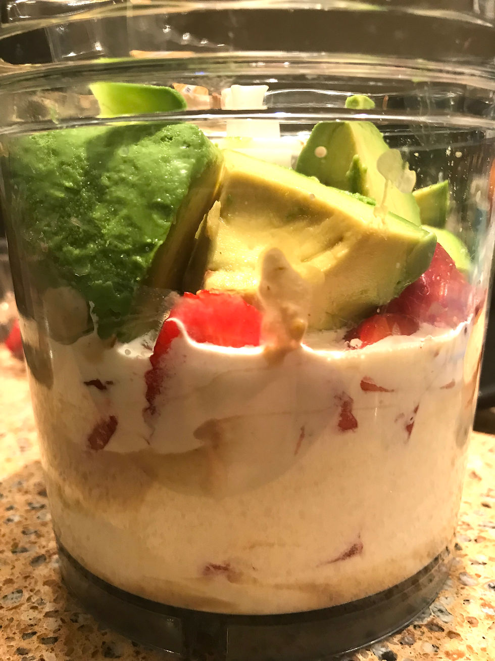 Image shows a blender container filled with heavy cream, strawberries, and avocado