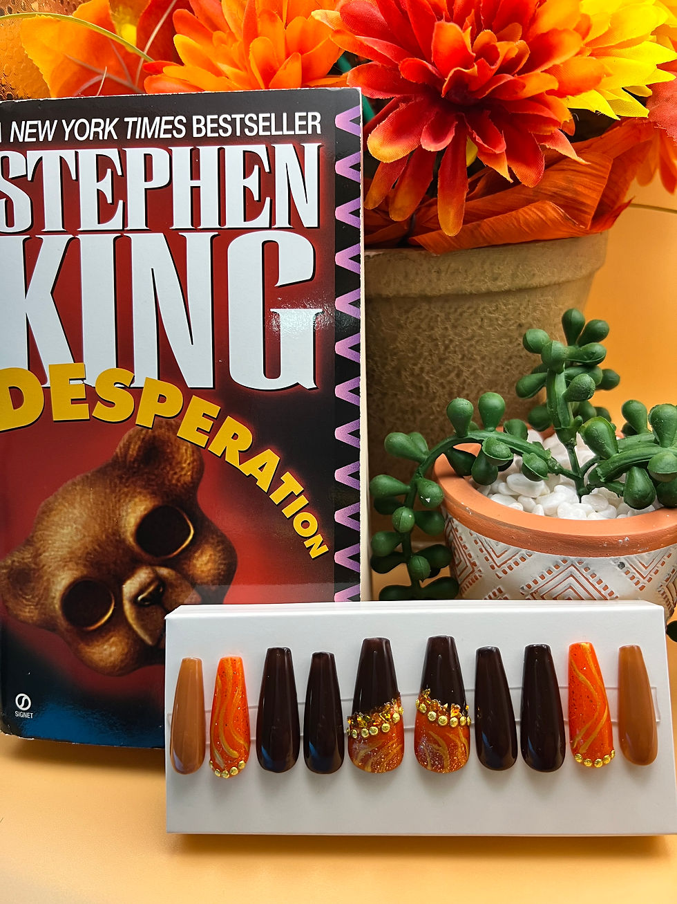 Coffin shaped press-on nails, brown, orange and tan colors on a display card