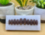 Short coffin, press-on nails in brown matte color with rhinestones on a nail display