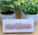 Blush colored, almond shaped press-on nails with rhinestones on a nail display