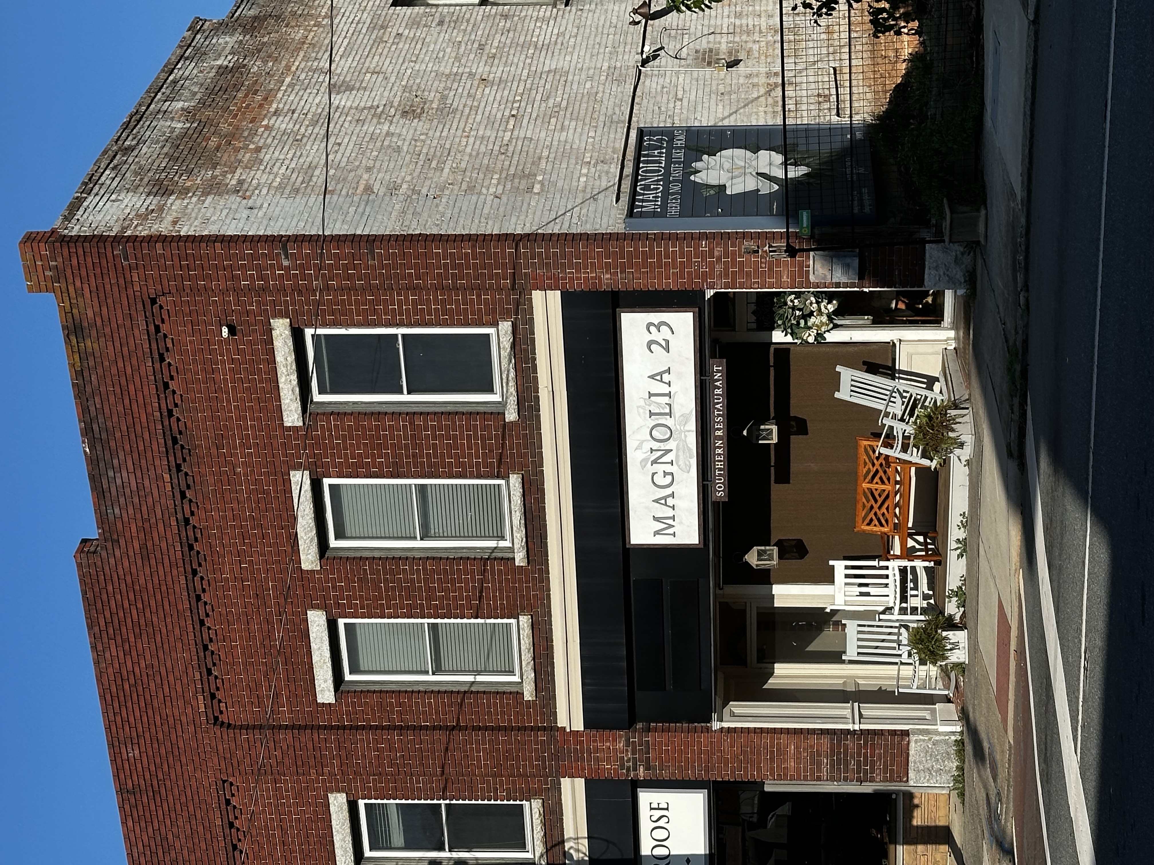 Magnolia 23 brick storefront, restaurant sign and porch seating in Asheboro.