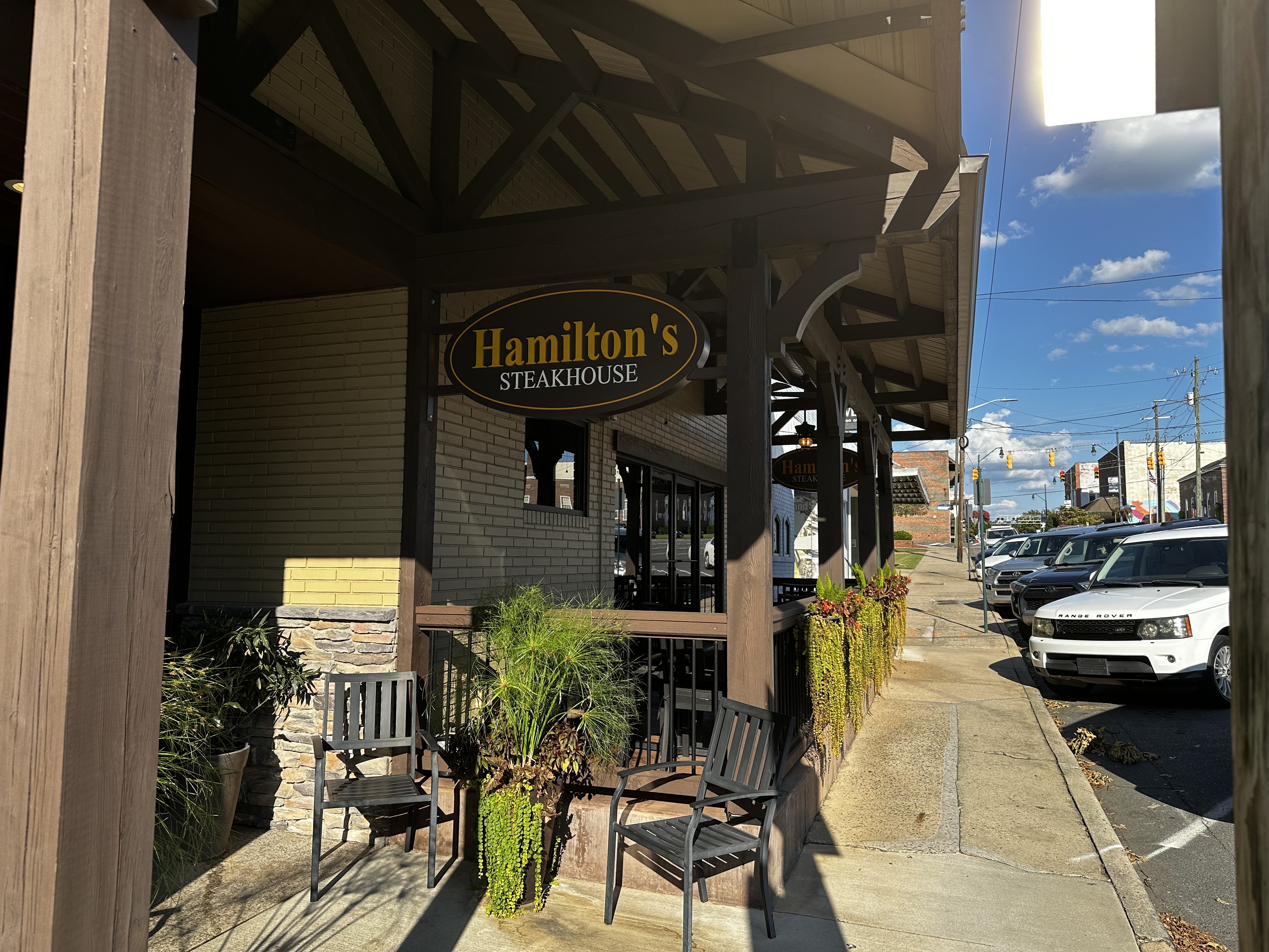 Hamilton’s Steakhouse sign, covered entrance and outdoor seating on Sunset Avenue.