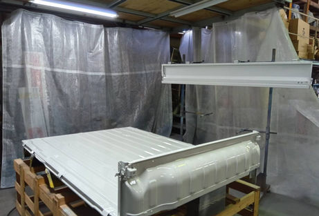 白いトラックの荷台、塗装された部品が置かれています、背景にカーテン、YouAuto-Base