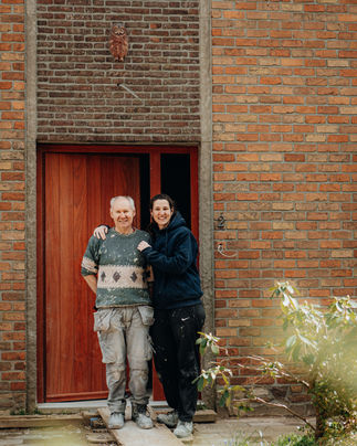 Man en vrouw staan glimlachend voor een gebouw.