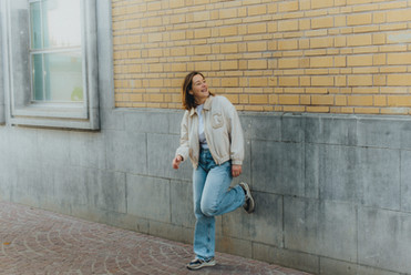 Lachende vrouw leunt tegen gele bakstenen muur
