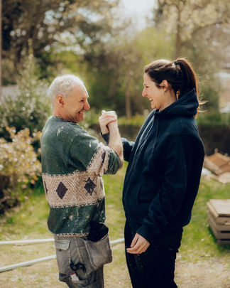 Man en vrouw schudden lachend handen buiten.