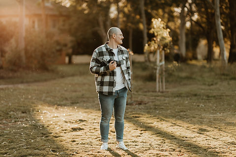 Bold Man standing on lawn with a sunset at the back