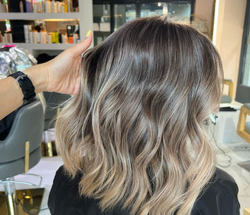Donna con capelli castani e biondi con mano sulla testa in salone