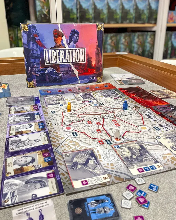 Spielübersicht mit Spielplan, Karten, Figuren, Chips und der Spielebox im Hintergrund.