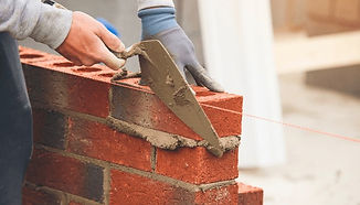 Mason laying red bricks with trowel