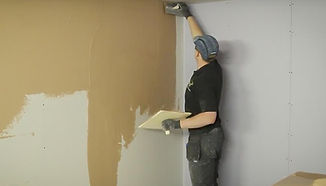 Plasterer applying compound to wall