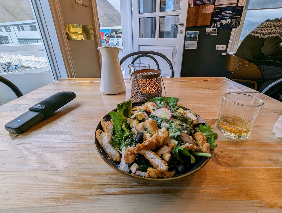A salad with chicken and a glass of scotch