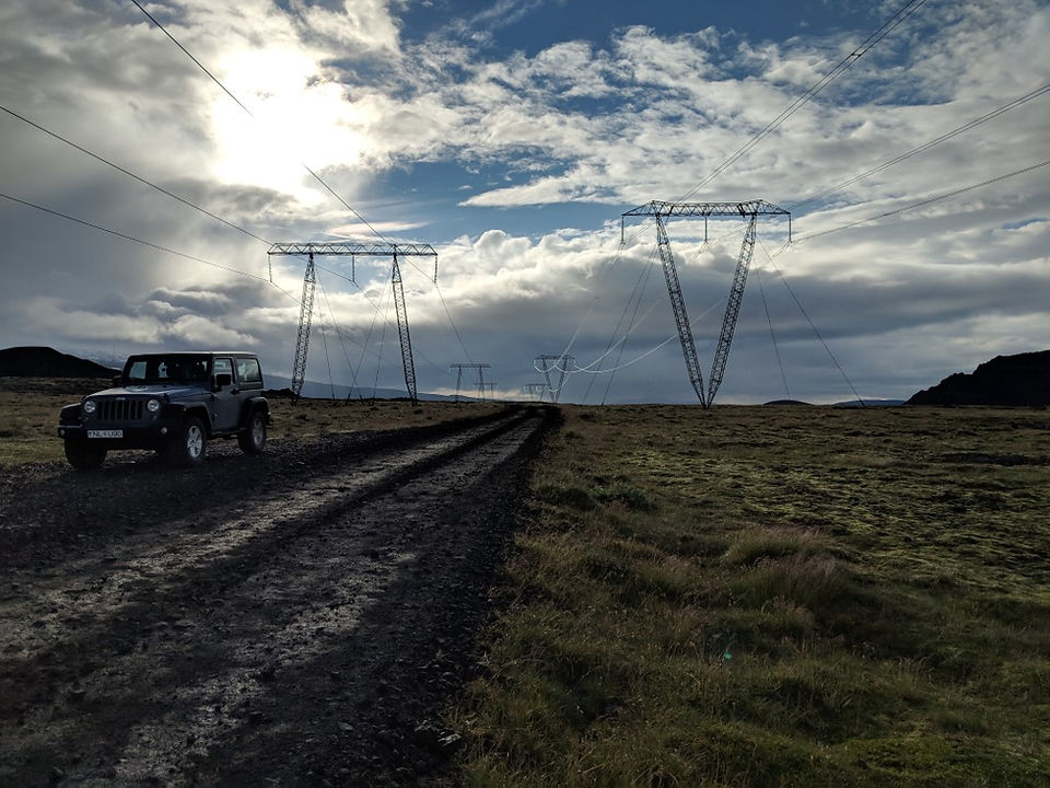 An f-road going through a series of powerlines with a jeep on it. 