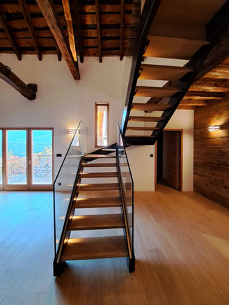 Escalier modèle ADN composé de limons métallique, marches en chêne massif et garde corps en verre