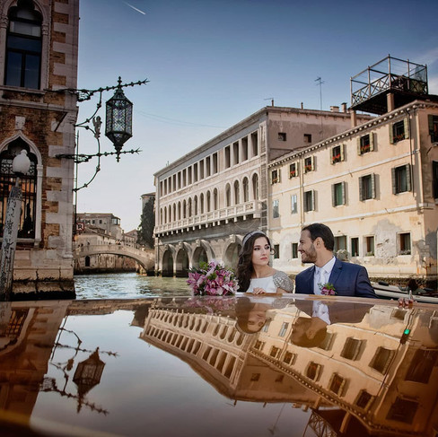 Carolina et Marco écCarolina et Marco naviguant en taxi sur le Grand Canal après leur mariage symbolique dans un palais privé à Venise, capturant l’atmosphère magique de la ville.hangeant leurs vœux lors de leur mariage symbolique dans le palais privé Ca’ Zenobio, un lieu empreint d’élégance et de romantisme à Venise.