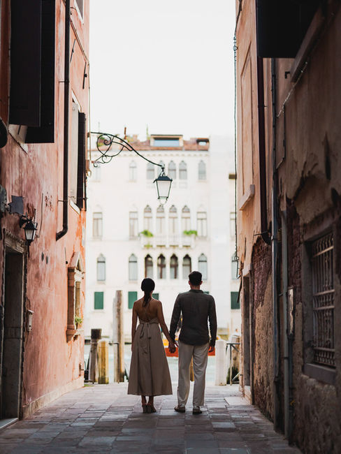 Balade intime d’un couple dans une ruelle colorée de Venise pendant leur séance photo de fiançailles