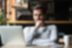 A thoughtful man sitting at his laptop researches the benefits of the debt avalanche method to pay off debts.