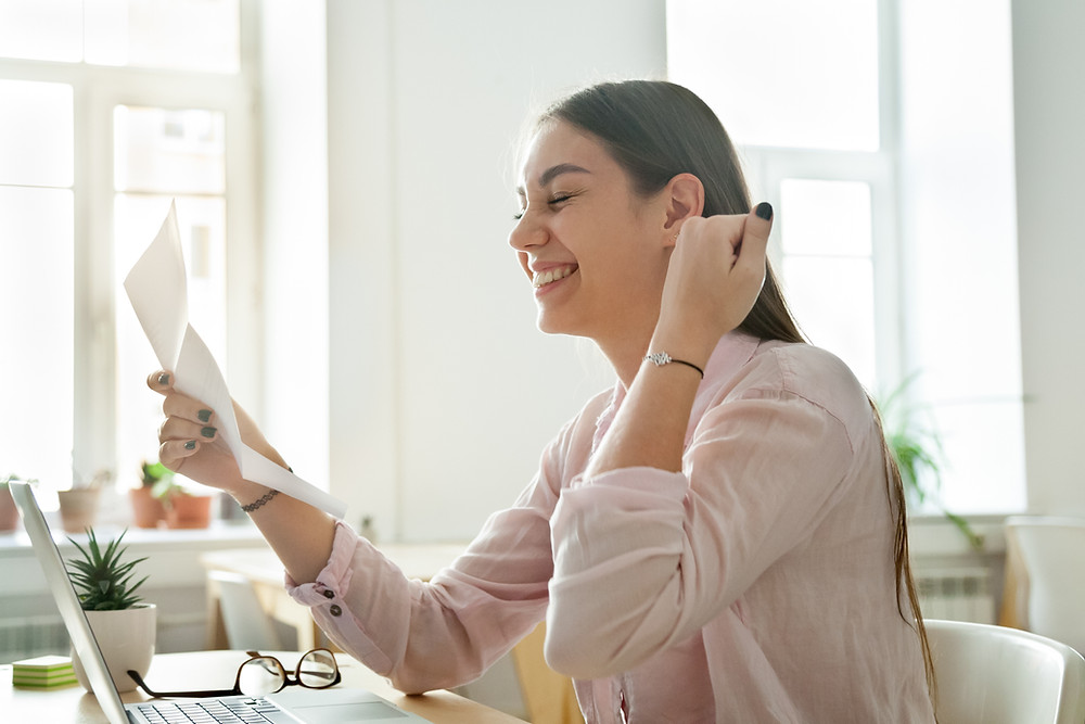 a woman happily reads an approval letter for the type of personal loan she hoped to receive to build her credit