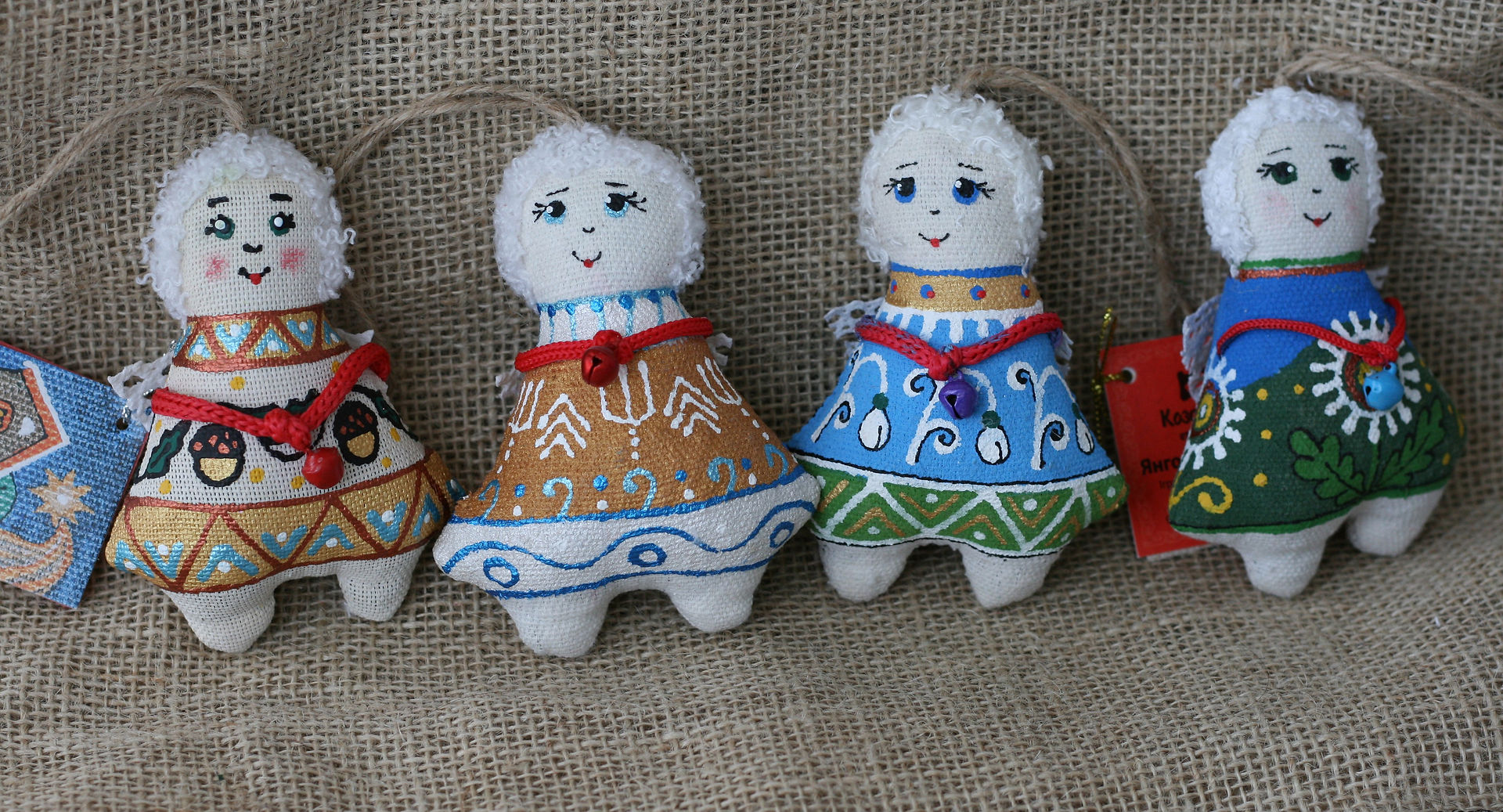 quatro anjos de tecido com sinos pintados em cores azul verde ouro e laranja