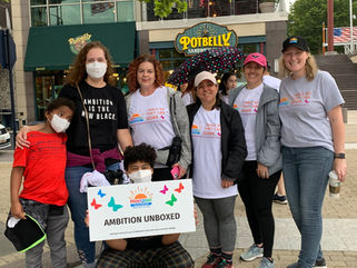 Ambition Unboxed members standing behind the team sign at the HorizonWalks 5K. 