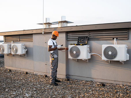 Black man checking air conditioner with digital multimeter