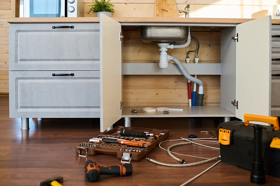 Open cabinet of kitchen counter with metallic sink and plastic pipes inside