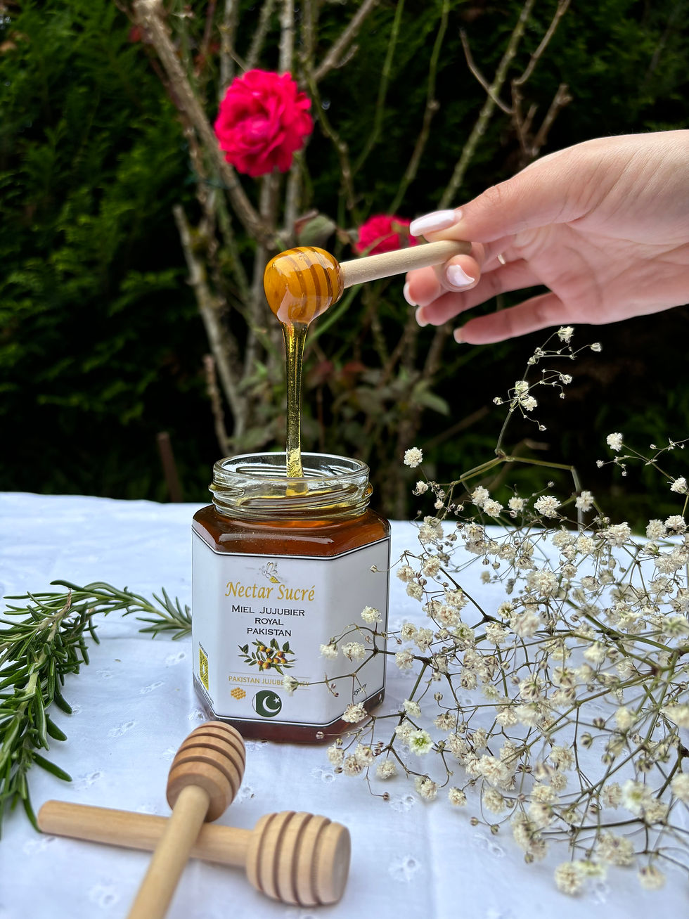 Miel de jujubier royal du Pakistan Nectar Sucré coulant d’une cuillère en bois au-dessus du pot ouvert.