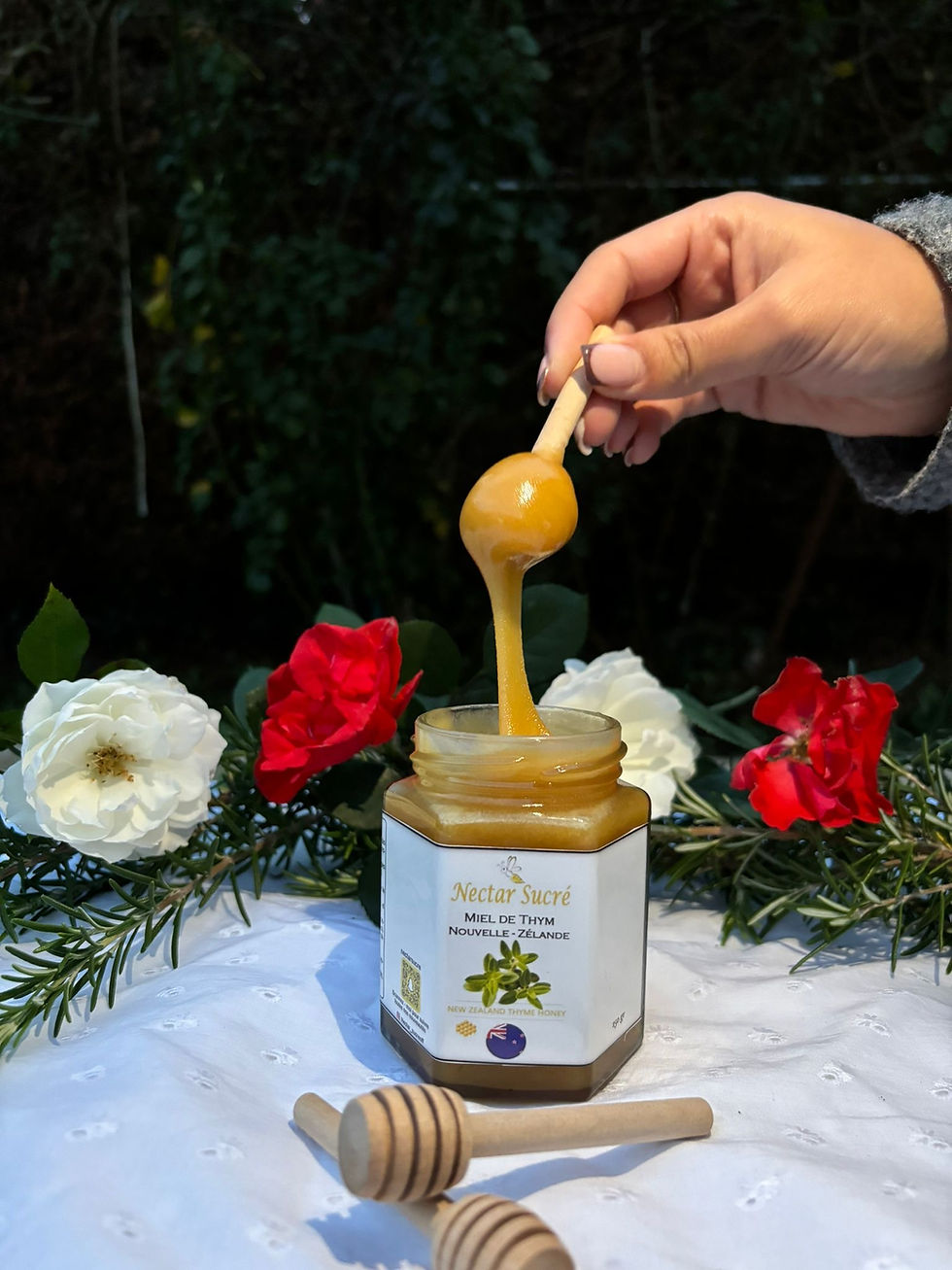 Miel de thym de Nouvelle-Zélande Nectar Sucré coulant d’une cuillère en bois au-dessus du pot ouvert.