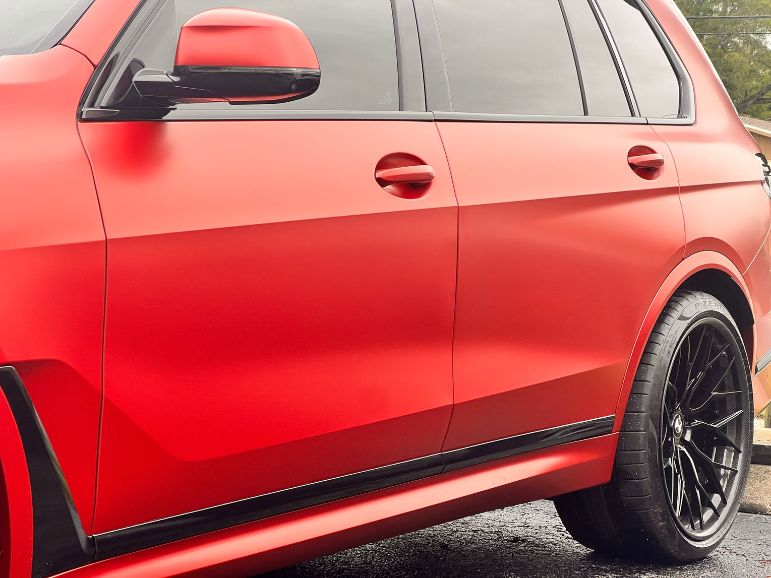 BMW SUV with a custom red car wrap and dark-tinted windows.