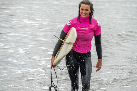 Surfer coming out of the water while holding her surf board