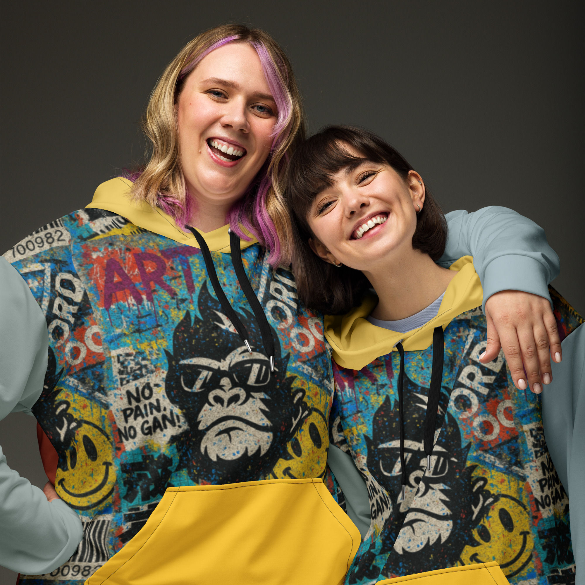 Two smiling women wearing Not My Monkey Oversized heavyweight sweatshirts, colorful graffiti background.