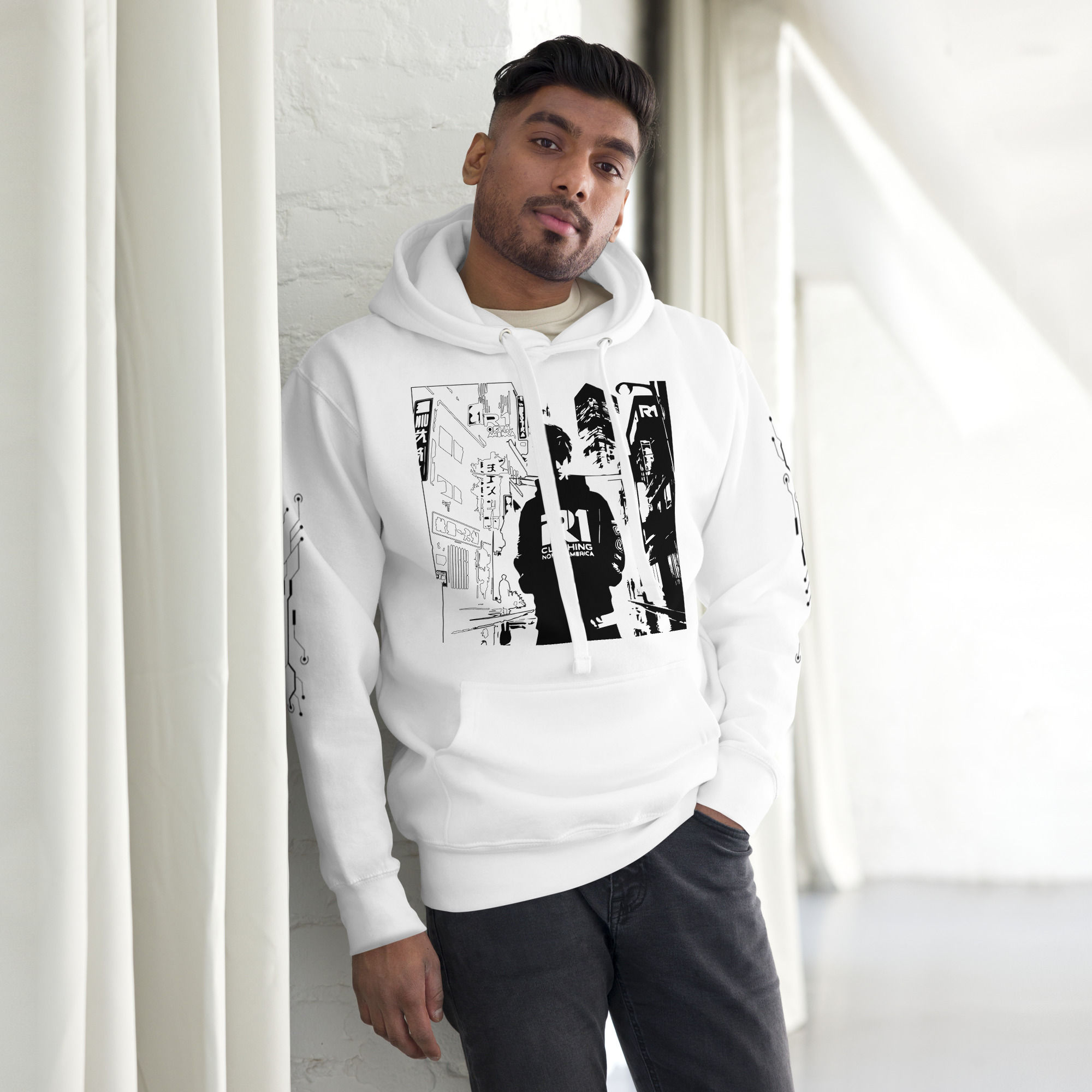 Man in white hoodie leaning on wall, artwork print on front.