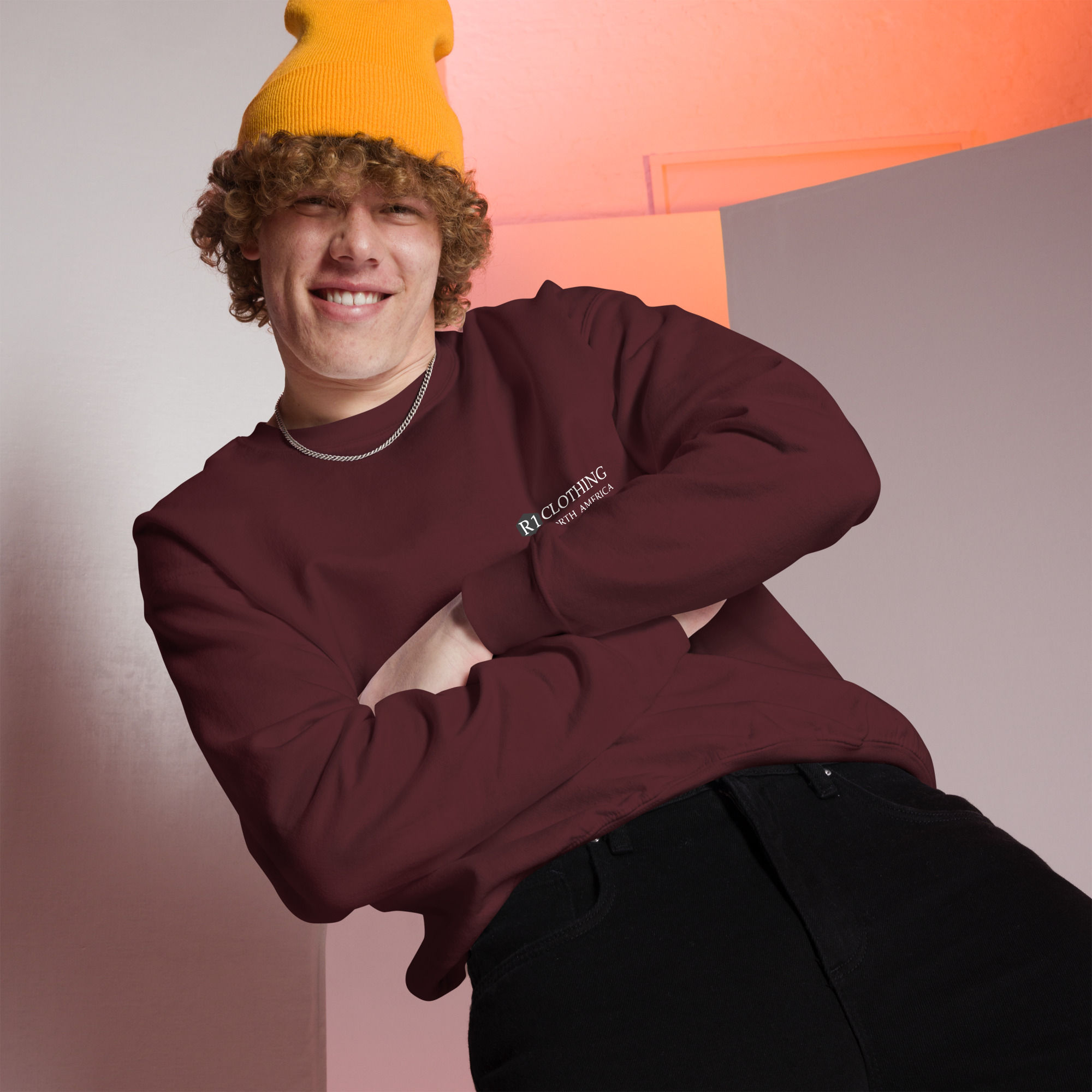Young man smiling, wearing burgundy sweatshirt and yellow beanie. www.r1clothing.com
