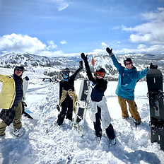 Celebrating with snowboarders on top of a mountain
